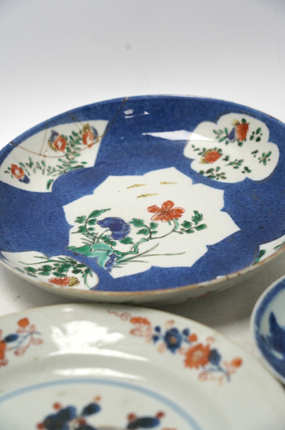 A Chinese powder blue famille verte dish, Kangxi period, a Yongzheng Imari plate and a Kangxi blue and white saucer, largest 22cm diameter. Condition - poor